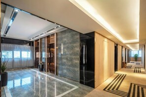 A modern hotel lobby with a marble floor, a reception desk, and a large window. - Shangjing Full Seasons Hotel (Xuzhou)
