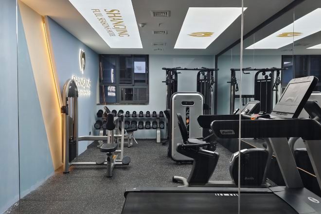 A gym with various exercise equipment, including dumbbells, a treadmill, and weight machines.