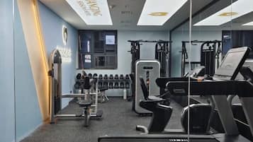 A gym with various exercise equipment, including dumbbells, a treadmill, and weight machines.
