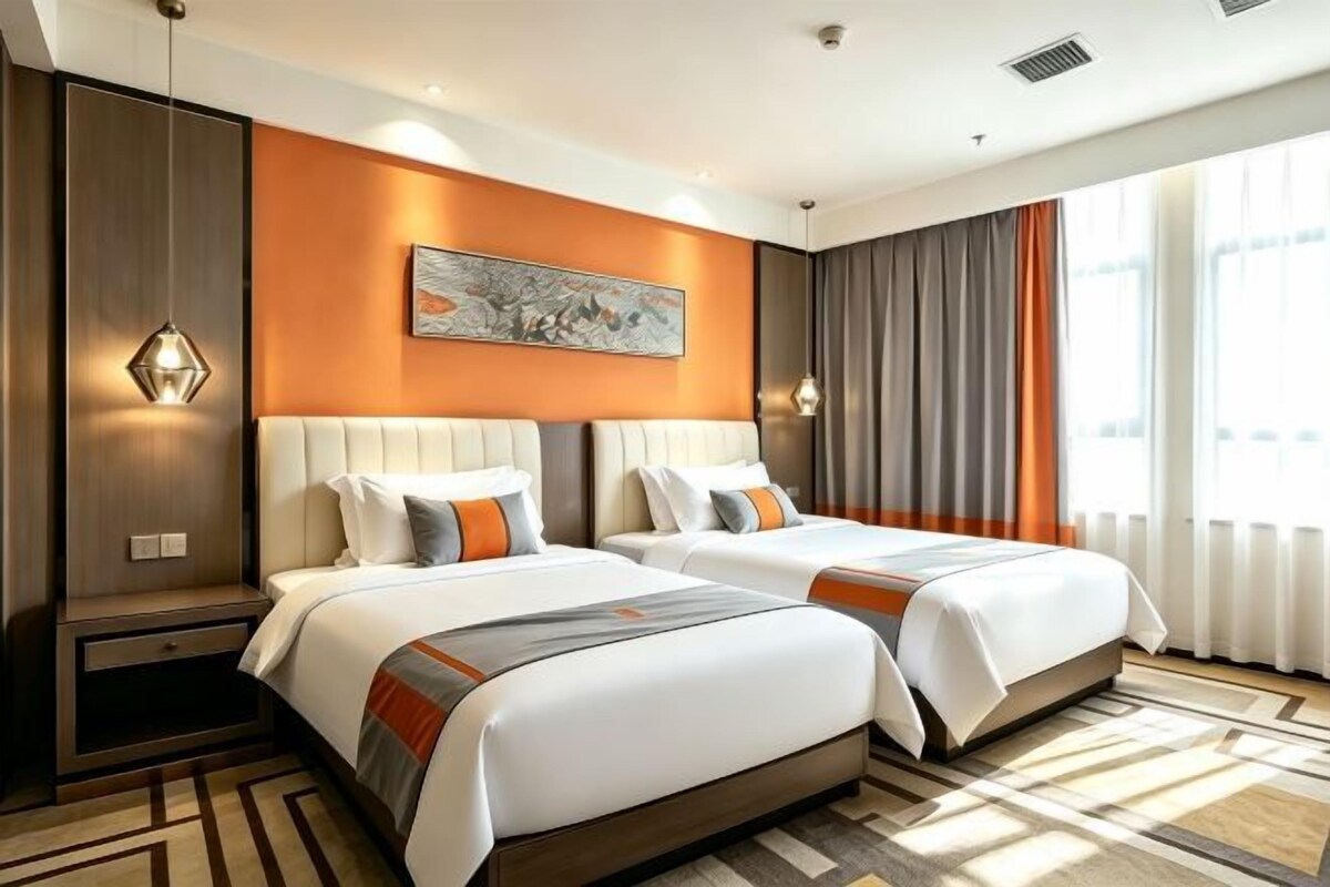 Ein Hotelzimmer mit zwei Betten, einem großen Fenster mit Vorhängen, einem Gemälde an der Wand und einem gemusterten Teppich.