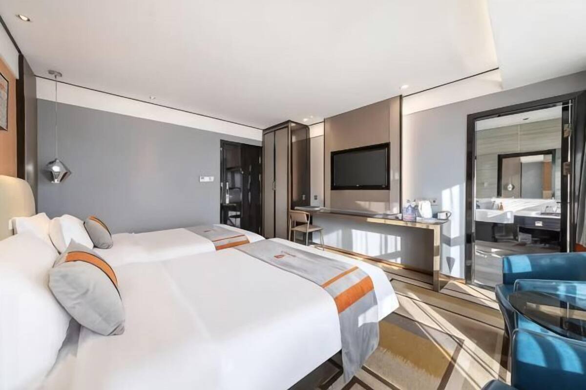 Une chambre d’hôtel avec deux lits, un bureau, une télévision et une salle de bain.