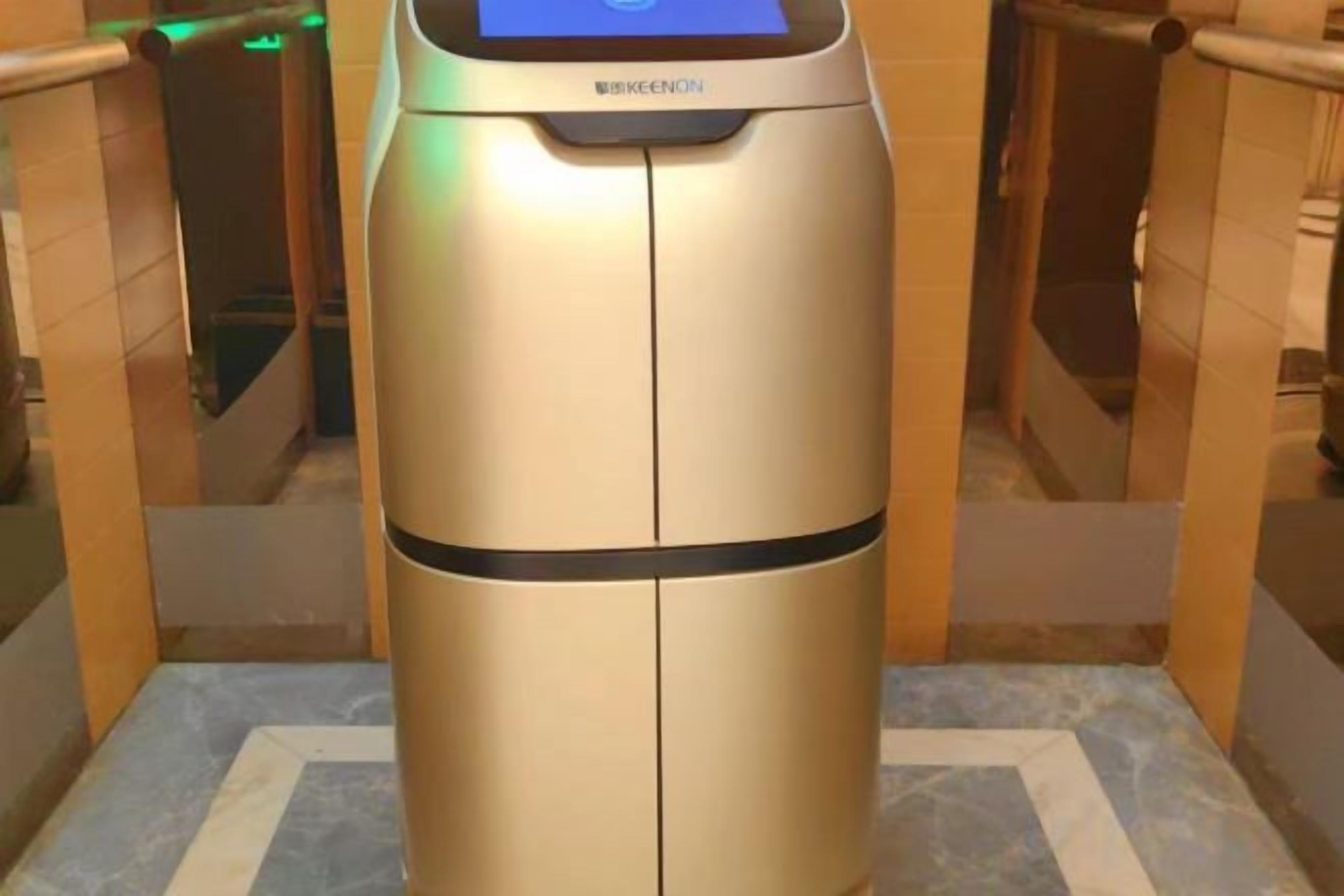 Un kiosque en libre-service doté d’une interface numérique, situé dans un couloir aux murs carrelés et au sol en marbre.