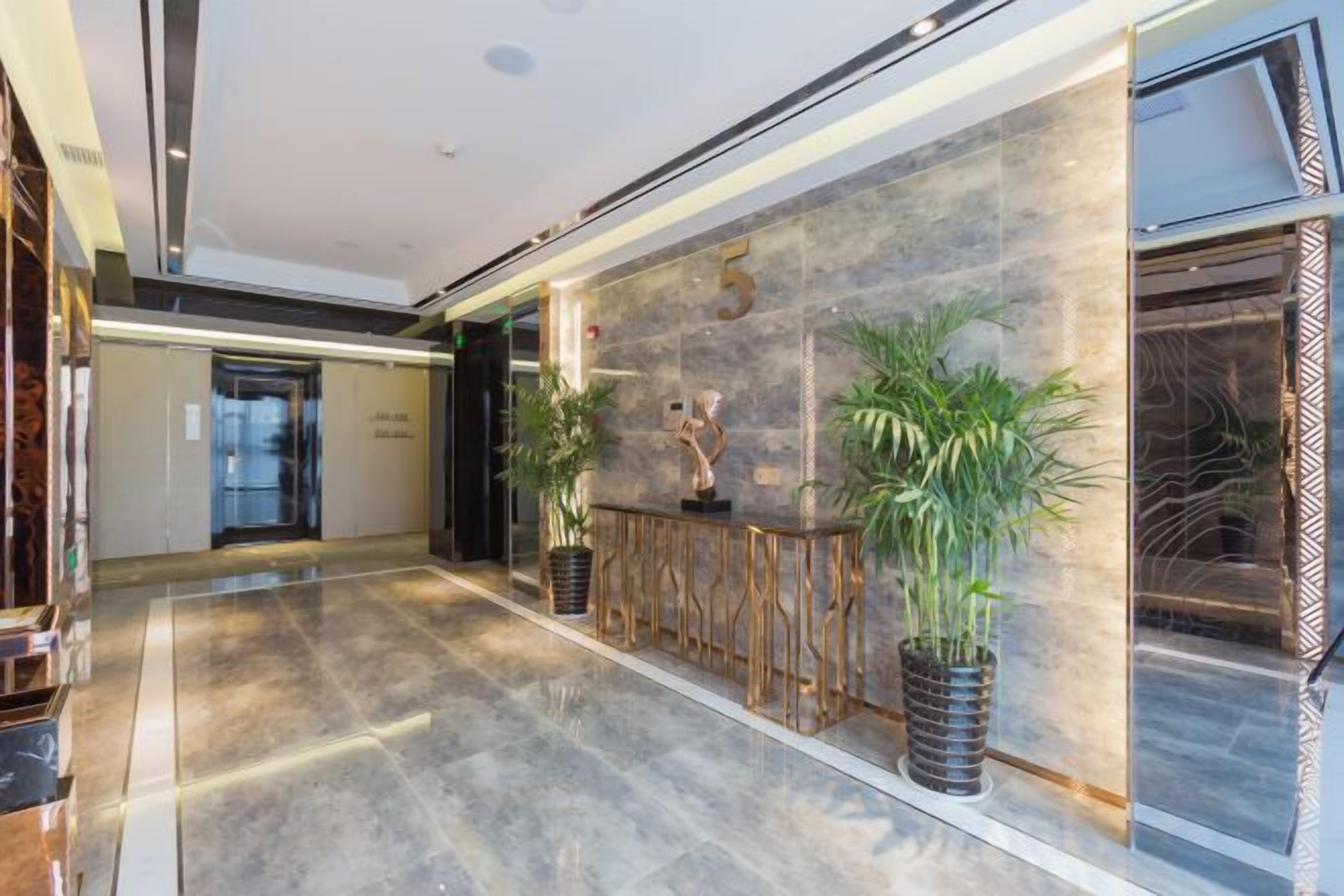 A hotel lobby with a marble floor, a reception desk, and a large wall with a number '5' sign.