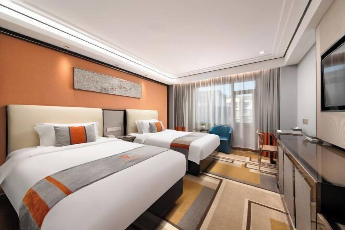 Une chambre d’hôtel avec deux lits, une télévision, un bureau et une chaise.