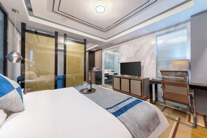 Une chambre d’hôtel moderne dotée d’un grand lit, d’un bureau, d’une télévision et d’une salle de bain visible à travers une porte en verre.