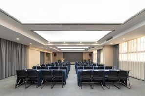 Ein Konferenzraum mit Tischen, Stühlen, großen Fenstern und hoher Decke.