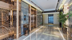 A spacious lobby with a marble floor, glass partitions, and a modern elevator. - Shangjing Full Seasons Hotel (Xuzhou)