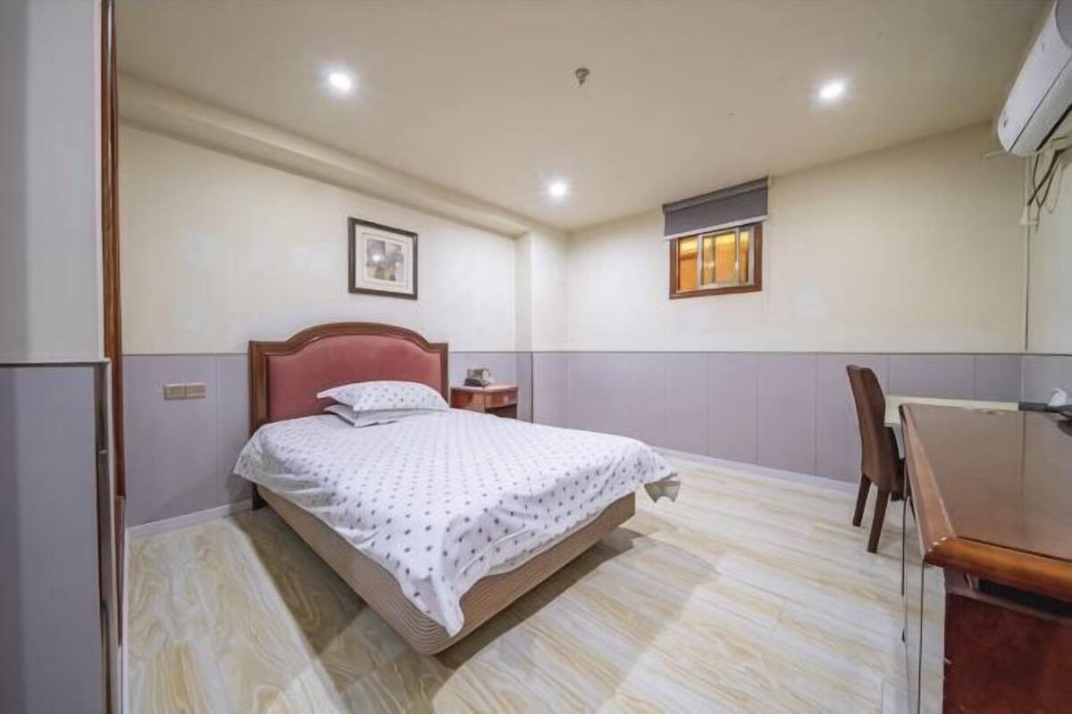 A bedroom with a bed, a desk, and a chair.
