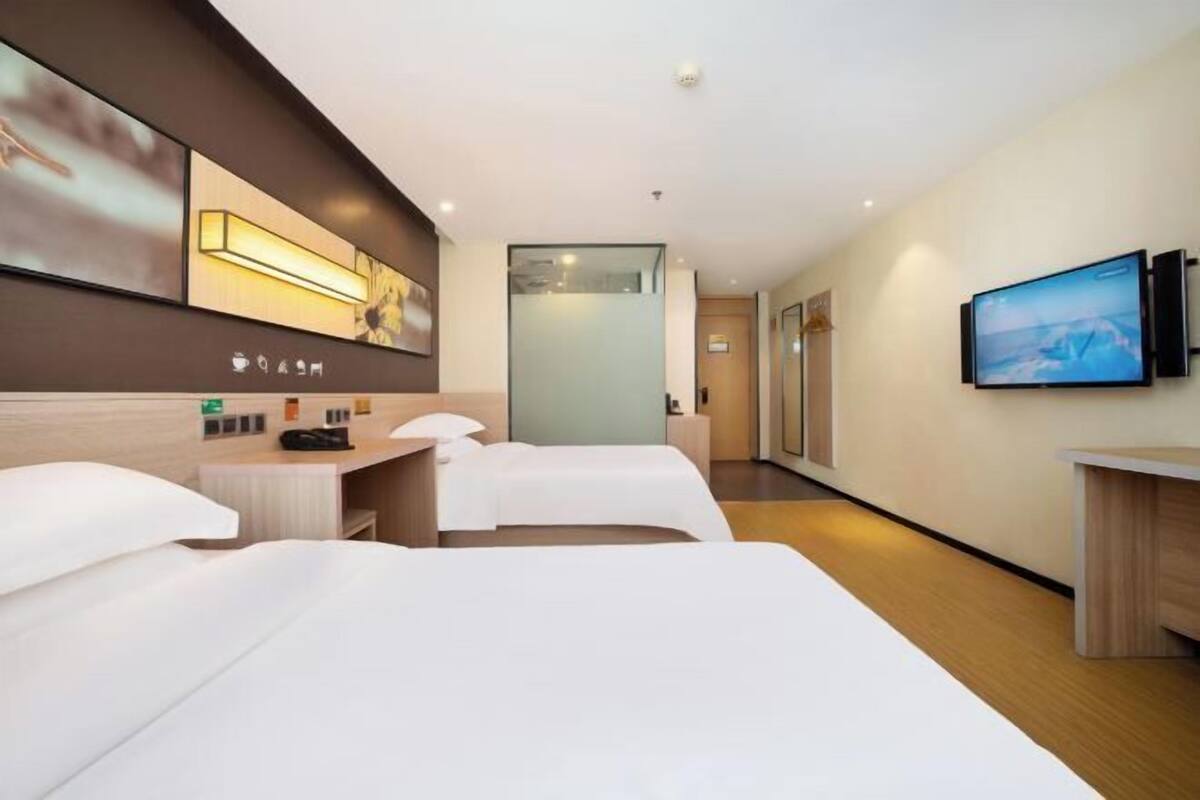 Une chambre d’hôtel avec deux lits, une télévision, un bureau et une salle de bain.