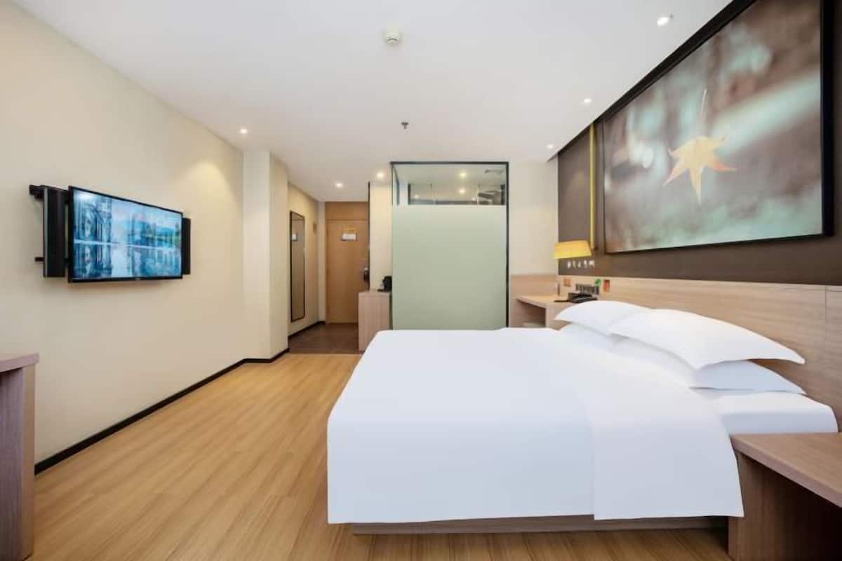 Une chambre d’hôtel avec un lit, une télévision, un bureau et une grande fenêtre.