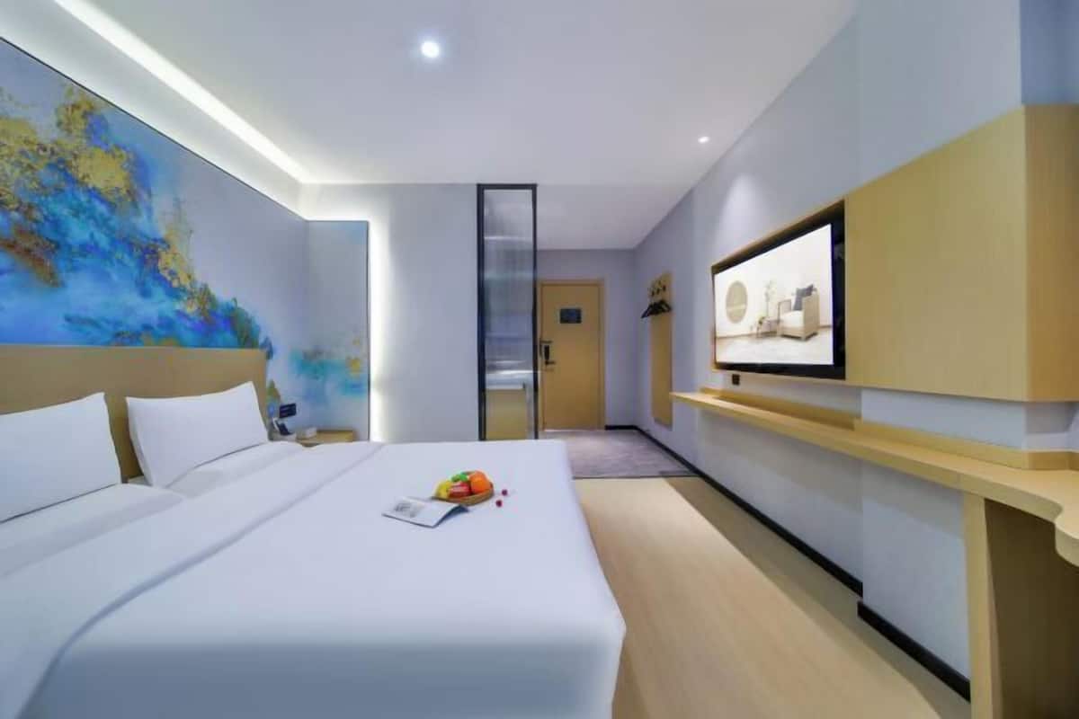 Une chambre d’hôtel avec un lit, un bureau, une chaise, une télévision et un tableau au mur.