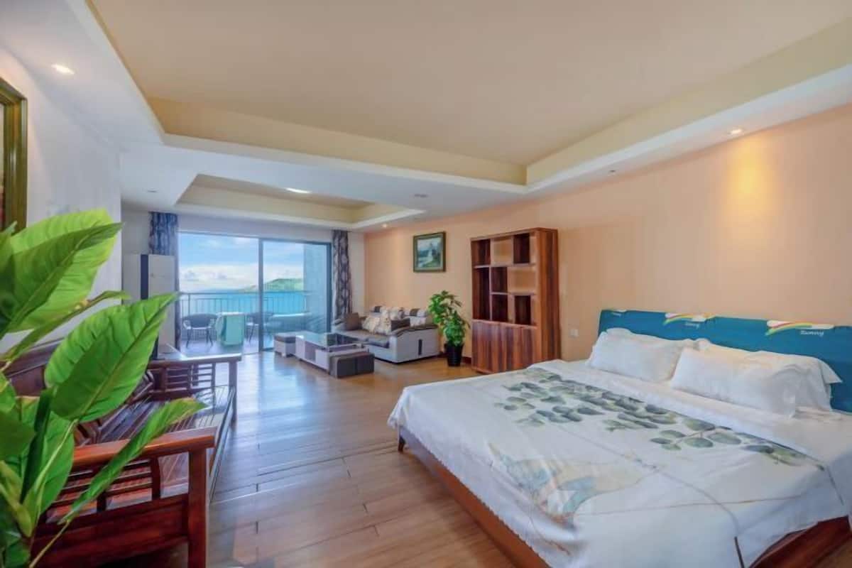 Ein Hotelzimmer mit einem großen Bett, einem Balkon, einer Sitzecke und einem Fernseher.