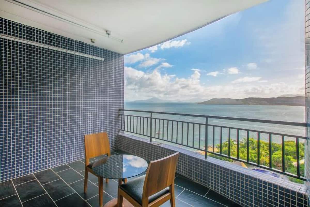 Ein Balkon mit Meerblick, ein runder Tisch, zwei Stühle und Fliesenwände.