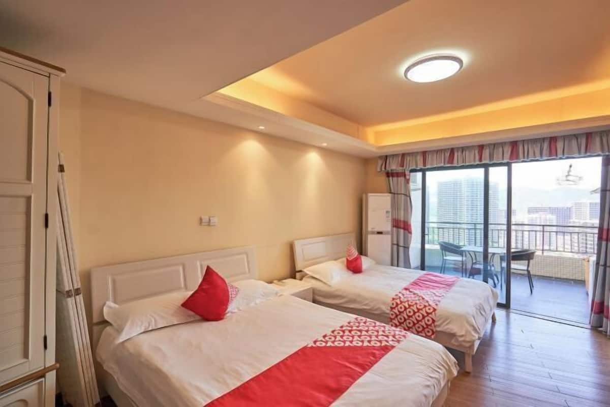Ein Hotelzimmer mit zwei Betten, einem Balkon mit Blick und einer Deckenleuchte.