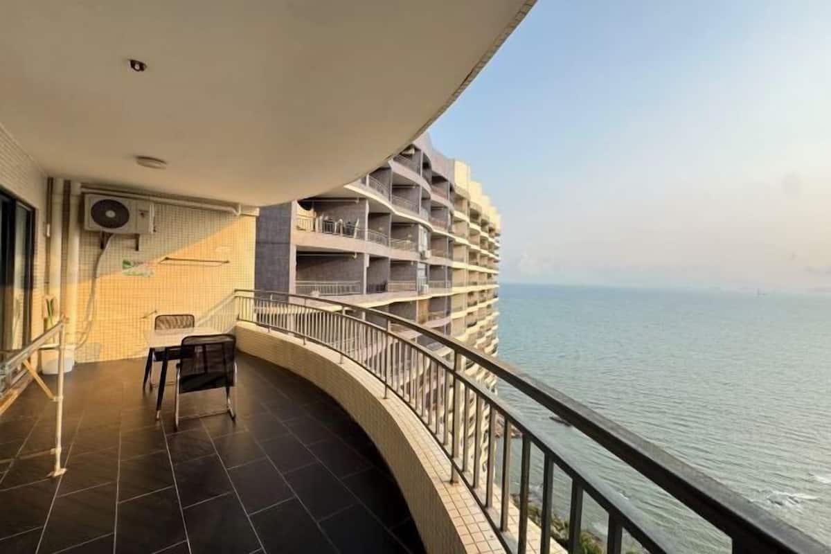 Ein Balkon mit Blick auf das Meer, ein Fliesenboden und ein Stuhl.