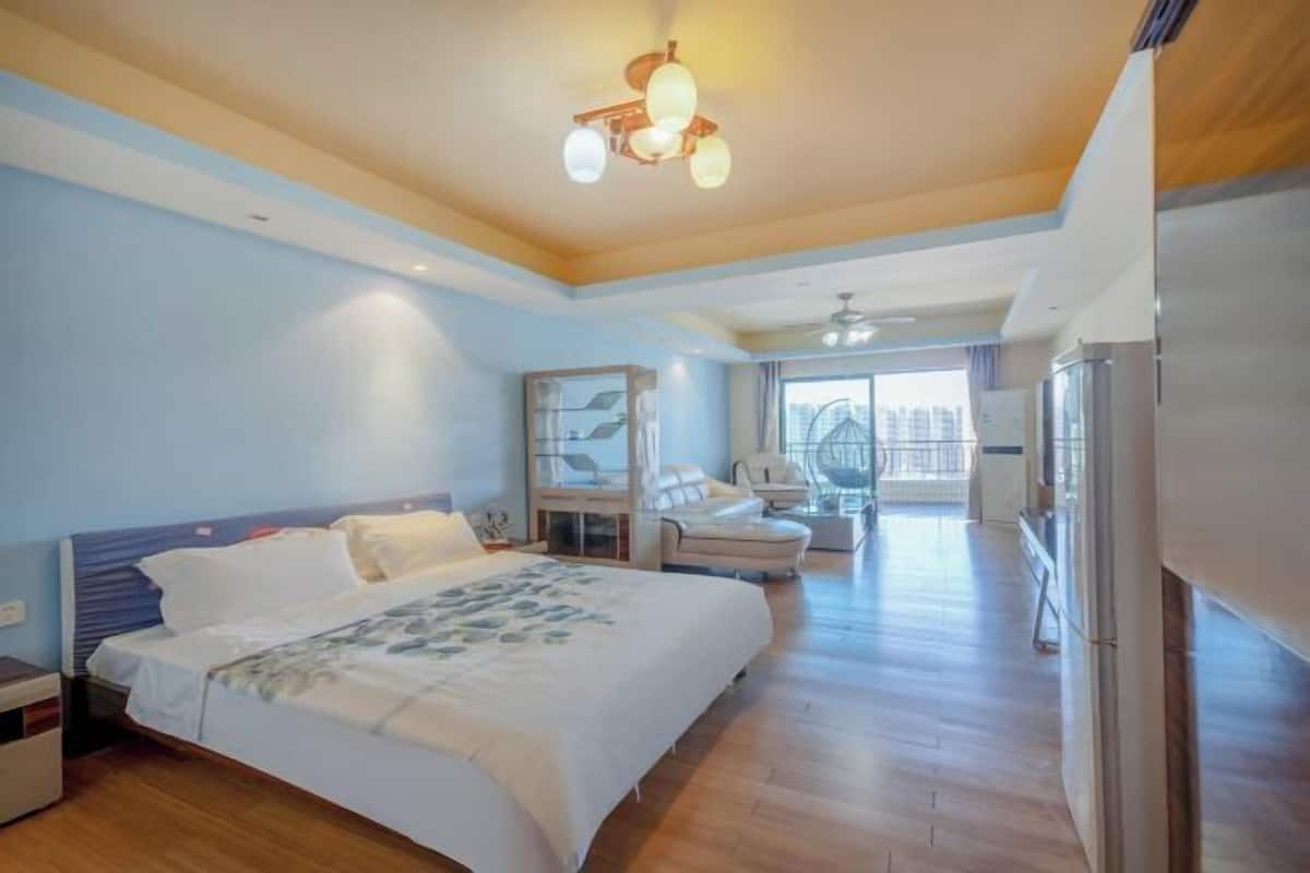 Ein geräumiges Schlafzimmer mit einem großen Bett, einem Deckenventilator und Blick auf die Stadt durch das Fenster.