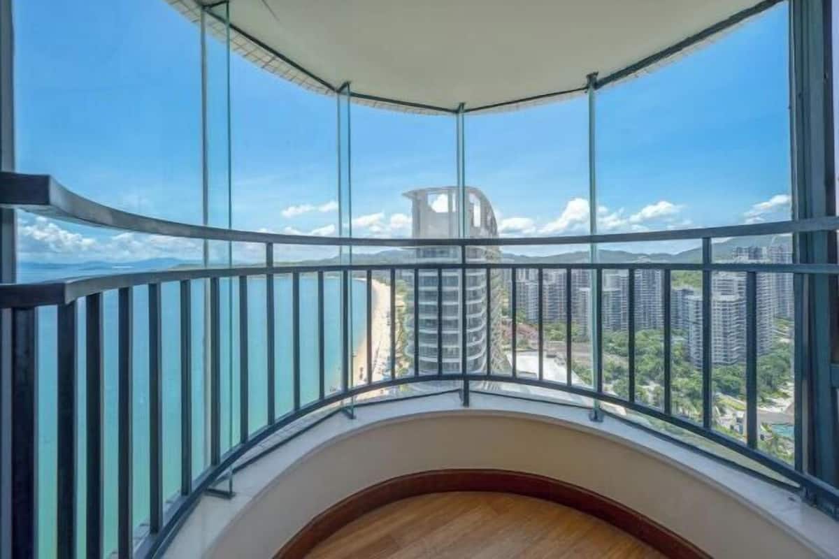 Ein Balkon eines Hochhauses mit einer geschwungenen Brüstung, der einen Blick auf umliegende Gebäude und einen klaren Himmel bietet.