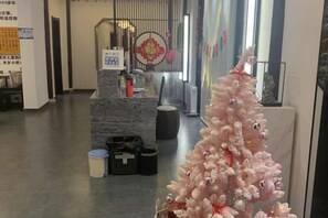 Un espace d’accueil avec un comptoir en marbre, un sapin de Noël rose et un mur décoratif.