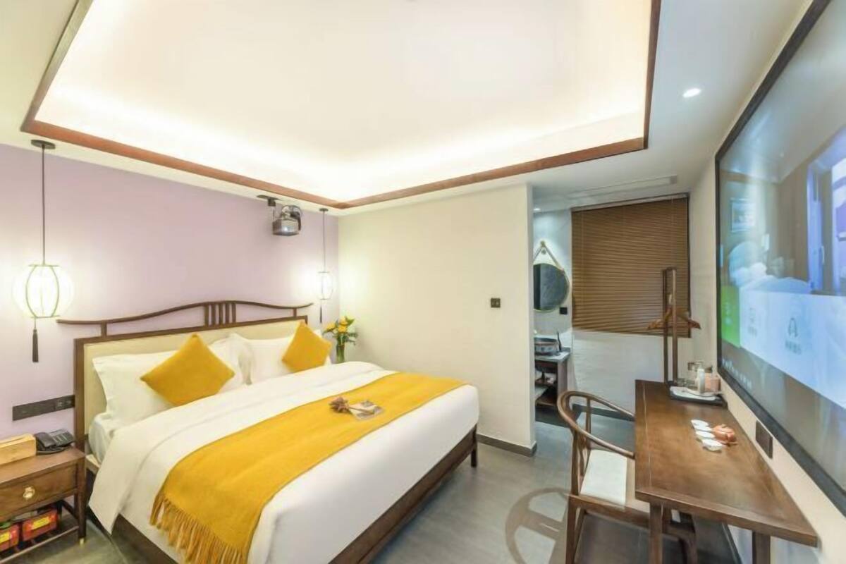 Una habitación de hotel moderna con una cama, una mesita de noche y un escritorio con una silla.