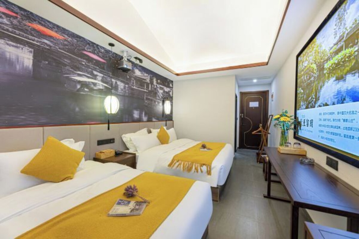 Habitación de hotel con dos camas, televisión, escritorio y un ventanal grande.