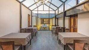 A restaurant with a glass ceiling, multiple tables, and chairs. - Tongli Cloud House Quadrangle Designer Cinema Hotel (Suzhou)