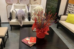 Una habitación con un conjunto de sofá, una mesa de centro con un florero y una mesita con libros.