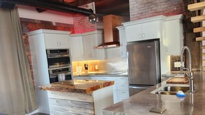 A kitchen with white cabinets, a stainless steel refrigerator, and a wooden island with a sink. - Rustic elegance (St Malo)
