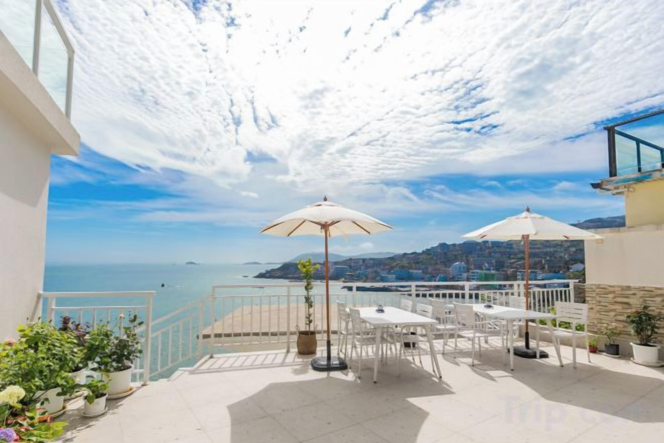 A terrace with outdoor furniture, a view of the sea, and a railing.