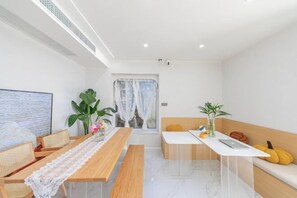 Un salon moderne avec une table à manger en bois, un canapé et un mur d’accent de couleur blanche.