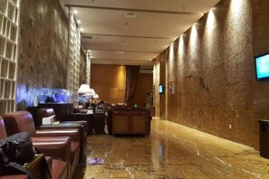 A hotel lobby with marble flooring, leather seating, a reception desk, and a television screen. - Blossom Seasons Club (Beijing)