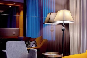 A hotel room with a sofa, a chair, a lamp, and a small table. - Blossom Seasons Club (Beijing)