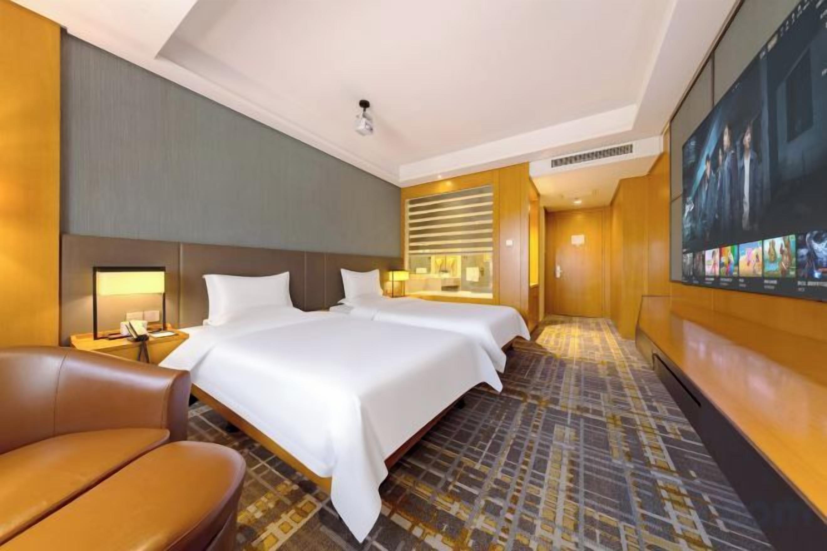 A hotel room with a large bed, a desk, a chair, and a television screen.
