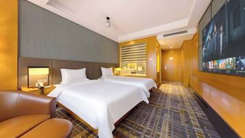 A hotel room with a large bed, a desk, a chair, and a television screen.