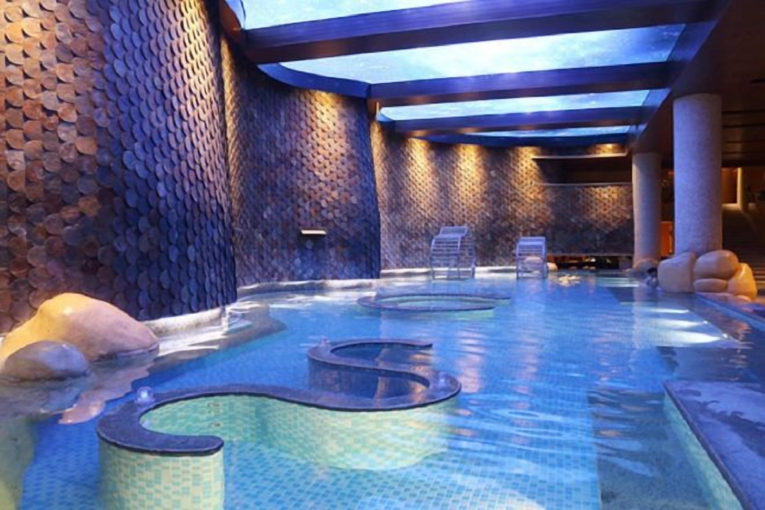 Zona de spa con jacuzzi, asientos y una pared de piedra.