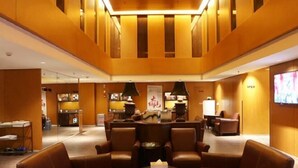 A lobby with leather seating, a central table, and a reception area with a counter and chairs. - Blossom Seasons Club (Beijing)