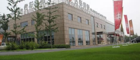 Un edificio moderno con tetto piatto, ampie finestre e un'area pavimentata di fronte.