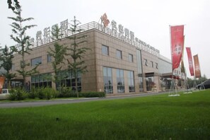 A modern building with a flat roof, large windows, and a paved area in front. - Blossom Seasons Club (Beijing)