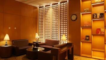 A lobby with seating, a clock, and a bookshelf.