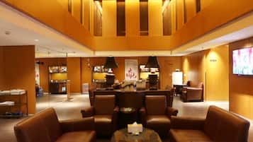 A lobby with leather sofas, a glass coffee table, and a reception desk.