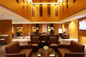 A lobby with leather sofas, a glass coffee table, and a reception desk. - Blossom Seasons Club (Beijing)