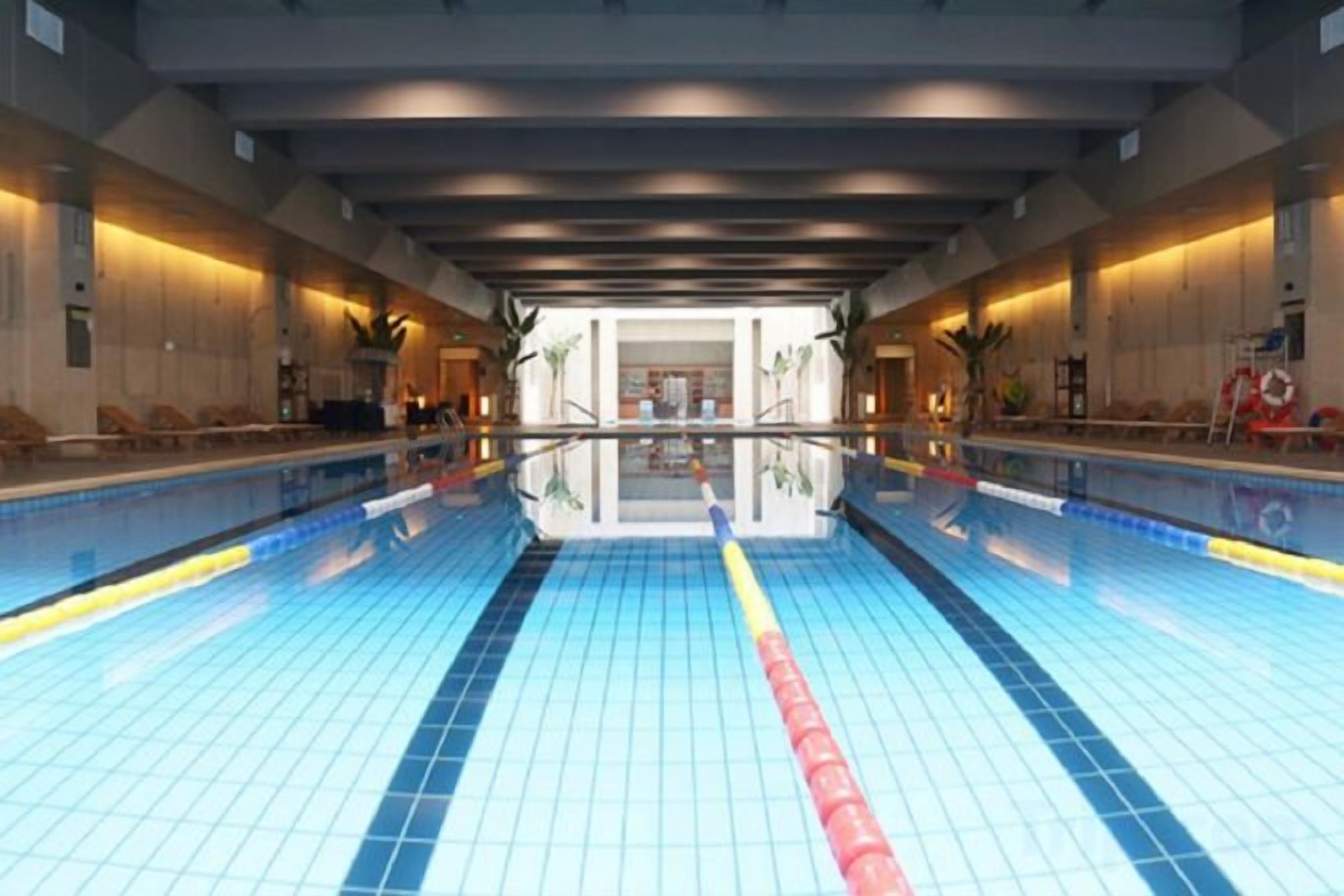 Una piscina interior con carriles delimitados, suelo de baldosas y techo con espejos.