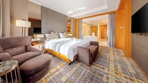 A modern hotel room with a large bed, a sofa, a small table, and a TV. - Blossom Seasons Club (Beijing)