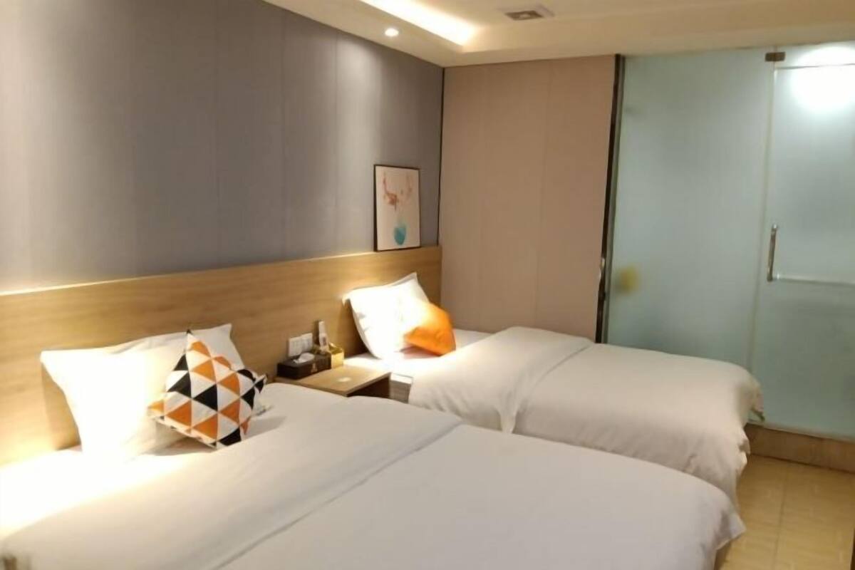 A hotel room with two beds, a nightstand, a framed picture on the wall, and a sliding door.