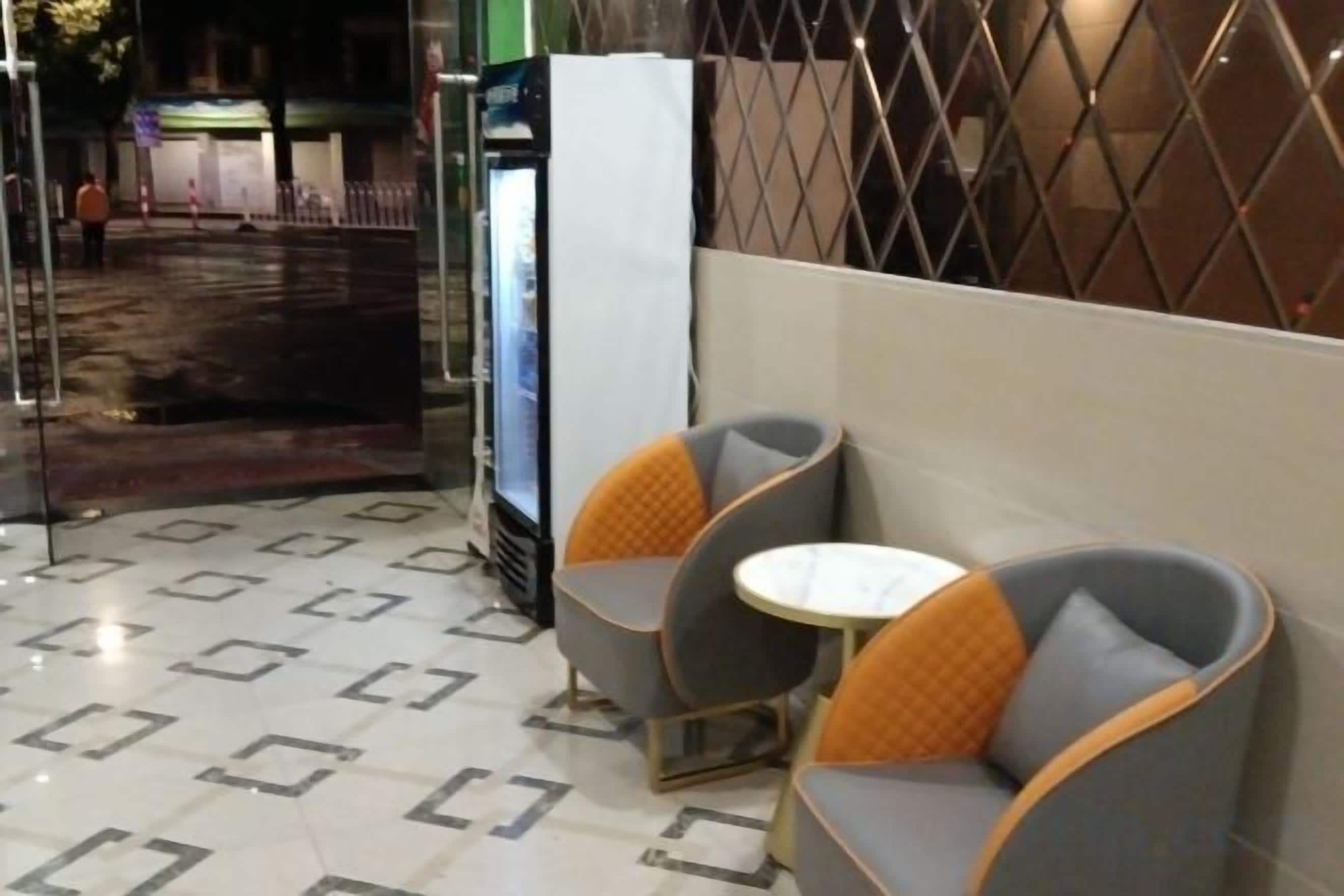 A seating area with cushioned chairs and a small table, a refrigerator, and a patterned floor.