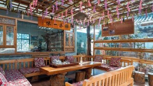 A traditional Chinese restaurant with wooden furniture, large windows, and hanging decorations. - Jizushan Funinglou Boutique Inn (Binchuan)