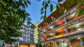 A traditional multi-story building with a courtyard, featuring balconies with railings and hanging lanterns. - Jizushan Funinglou Boutique Inn (Binchuan)