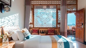 A bedroom with a bed, pillows, a nightstand, a vase with flowers, and a window with a geometric design. - Jizushan Funinglou Boutique Inn (Binchuan)