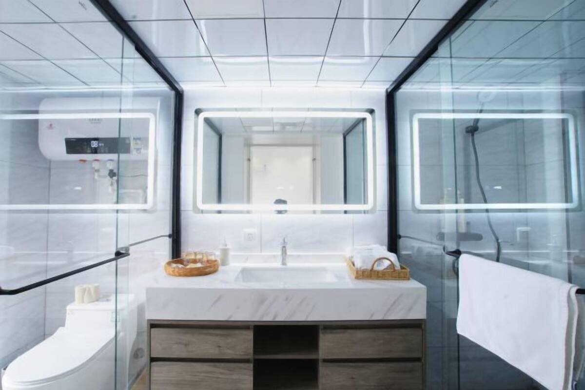 A modern bathroom with a glass enclosure, a dual sink vanity, a mirror, and a towel rack.