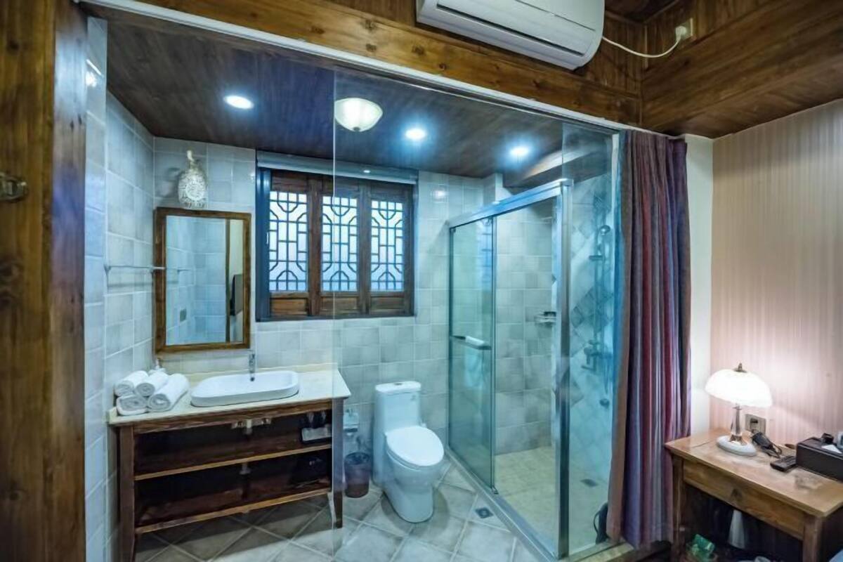 A bathroom with a wooden vanity, a toilet, a glass shower enclosure, and a mirror.