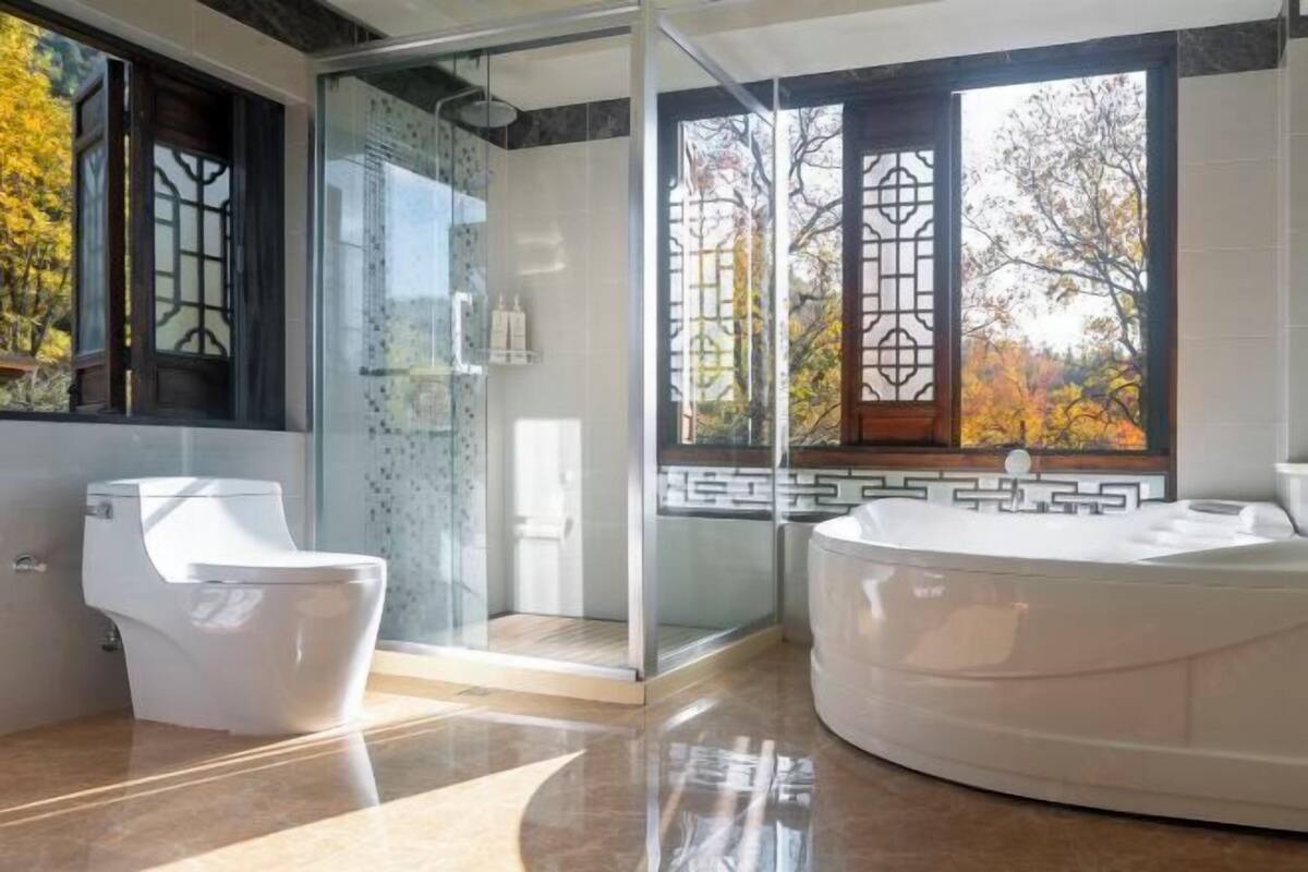 A modern bathroom with a glass shower enclosure, a toilet, and a large bathtub.